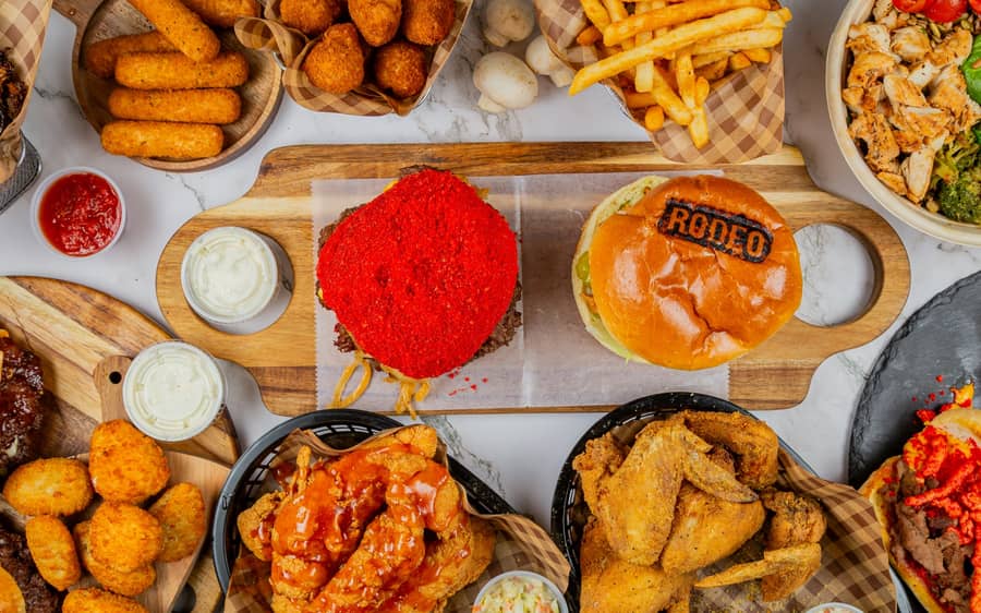 A spread of Rodeo Burgers and Chicken smash burgers, wings, and sides